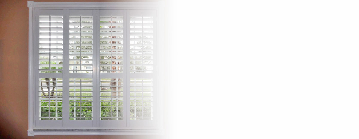 White plantation shutters on window with outdoor foliage